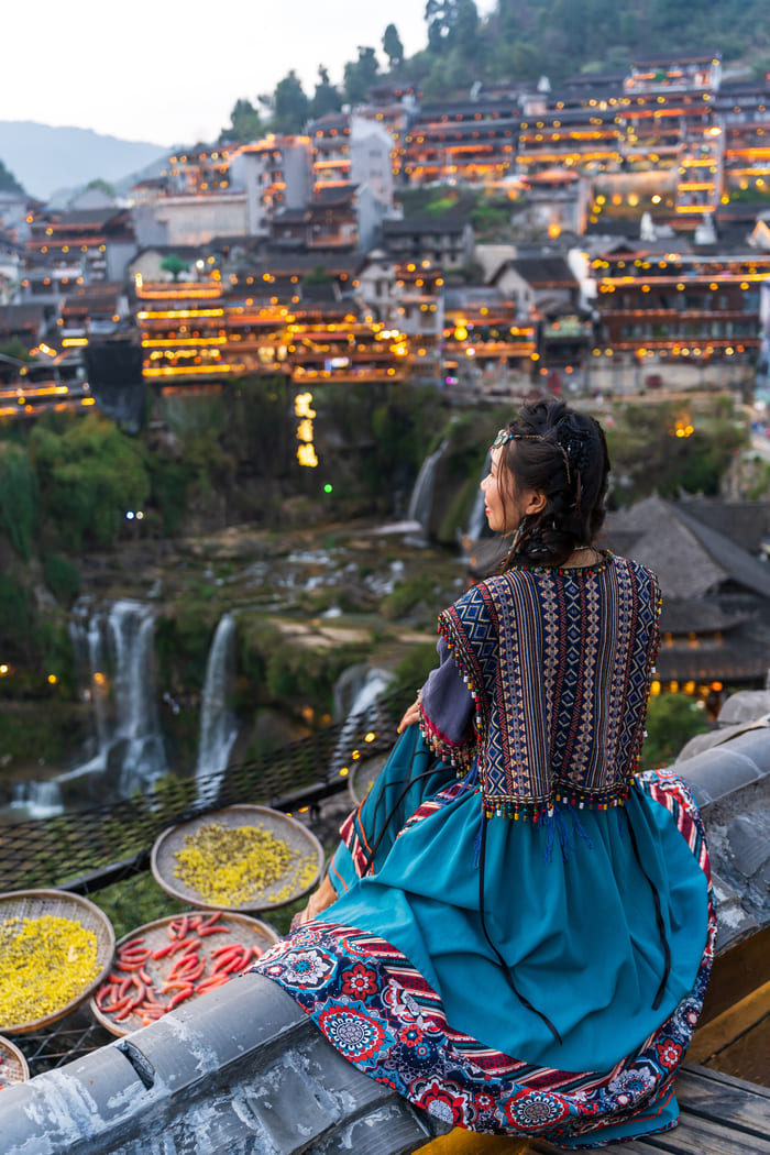 mujer al atardecer en China mirando hacia la ciudad de lijiang